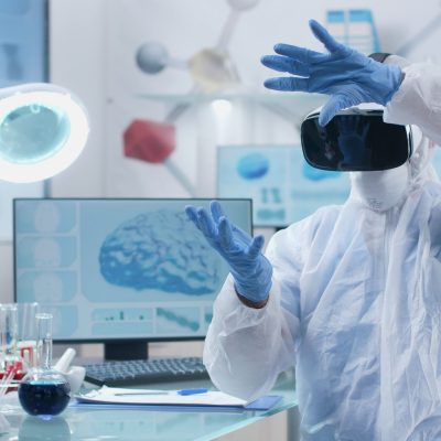 Scientist researcher wearing virtual reality headset analyzing brain activity futuristic holografic interface during chemistry experiment in biochemistry hospital laboratory. Neuroscience research