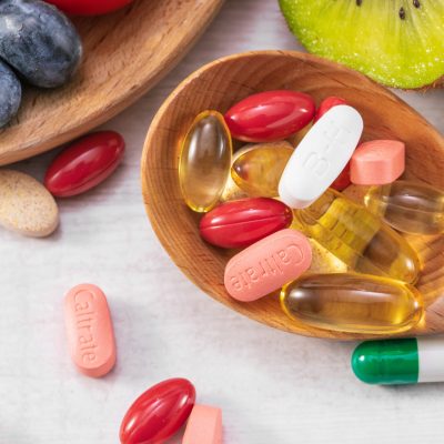 A closeup shot of fresh fruits with different medicine on a wooden spoon